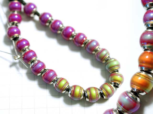 BM203SW　ムードビーズ　６ｍｍ　赤系<br>温度によって色の変化するカラーチェンジビーズです。サーモ熱変化ビーズとでも呼ぶべきでしょうか？<br>気温によって深紅から淡緑など様々に変わります。こちらは暖色系。<br>同タイプのビーズとも色変化域が多少異なるようです。<br>画像のマス目は５ｍｍ四方です。大きさの目安にして下さい。<br>６ｍｍ×６．２ｍｍ<br>